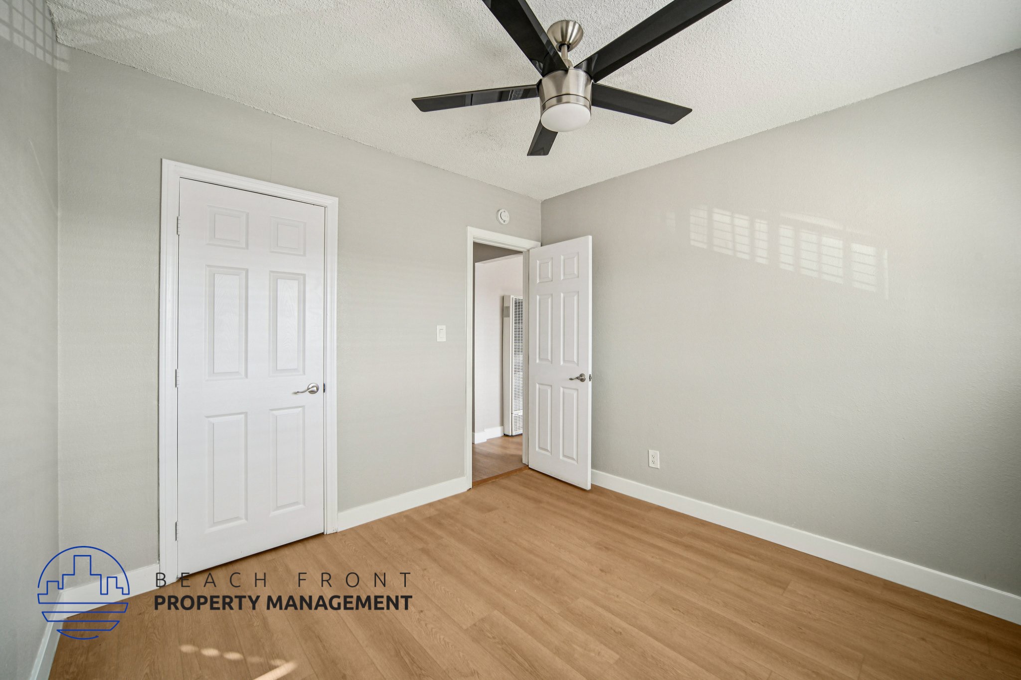A room with a ceiling fan and two doors.